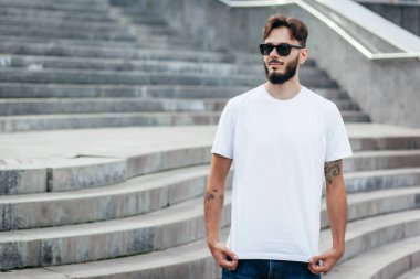 Beyaz tişörtlü ve gözlüklü, sakallı, şık bir genç. Sokak fotoğrafı