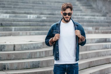 Beyaz tişörtlü ve gözlüklü, sakallı, şık bir genç. Sokak fotoğrafı