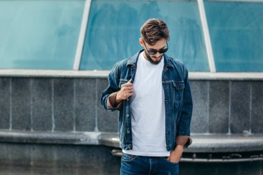 Beyaz tişörtlü ve gözlüklü, sakallı, şık bir genç. Sokak fotoğrafı