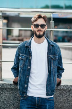 Beyaz tişörtlü ve gözlüklü, sakallı, şık bir genç. Sokak fotoğrafı