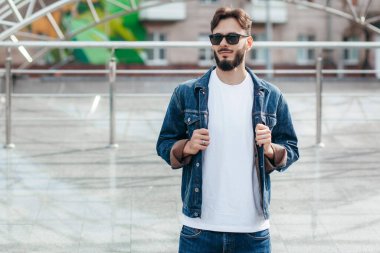 Beyaz tişörtlü ve gözlüklü, sakallı, şık bir genç. Sokak fotoğrafı