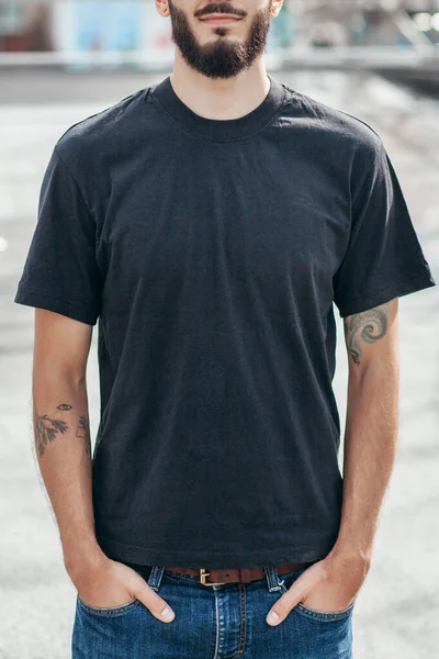 A stylish man with a beard  with a black T-shirt. Street photo