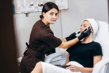 Güzellik uzmanı kadın kozmetik kabinesindeki güzel modellerin kaşlarını düzeltiyor.