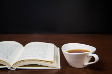 bir fincan kahve ile masa üzerinde açık bir kitap