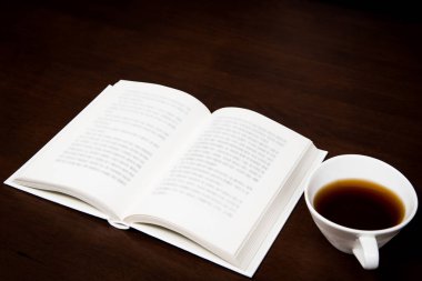 bir fincan kahve ile masa üzerinde açık bir kitap