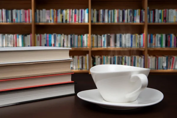 Bücher gestapelt auf dem Schreibtisch mit einer Tasse Kaffee. — Stockfoto
