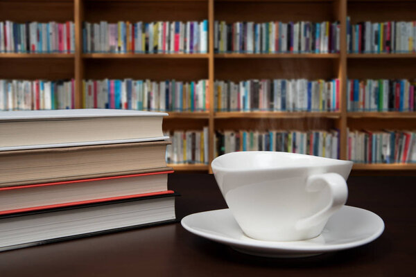 books stacked on the desk with a cup of coffee.