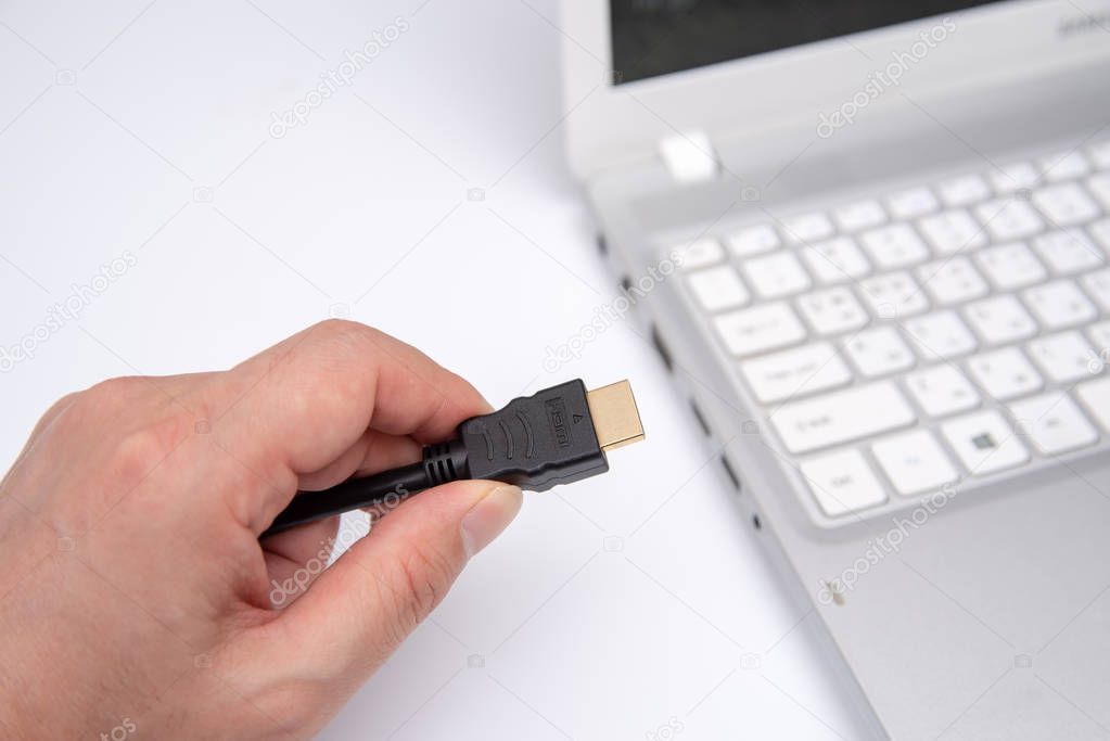 Man is connecting black hdmi cable into laptop