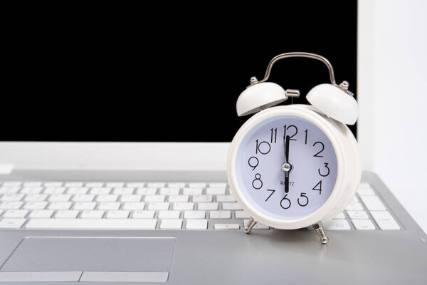 Alarm clock and portable computer put on the desk, with white background.
