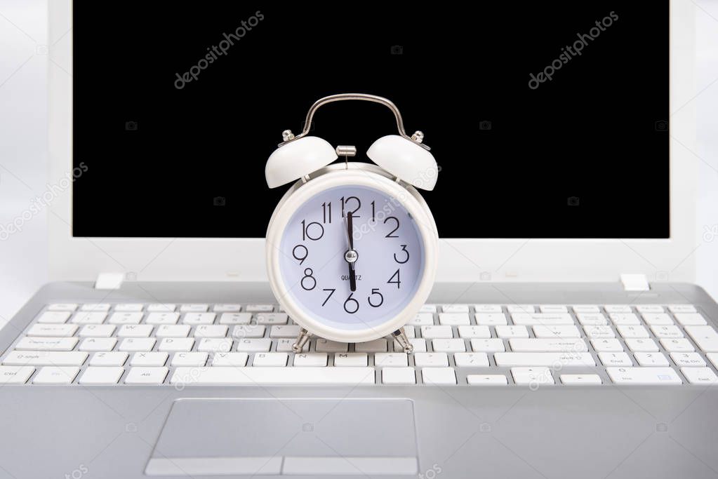 Alarm clock and portable computer put on the desk, with white background.