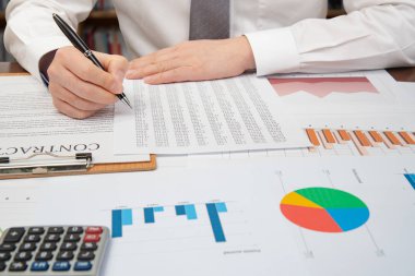 İşyeri iş adamı. Sözleşmeler, çizelgeler ve grafikler masanın üstüne.