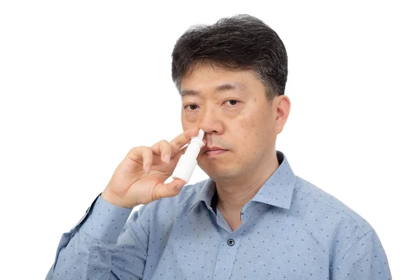 En man som håller en nässpray i handen på vit bakgrund. — Stockfoto