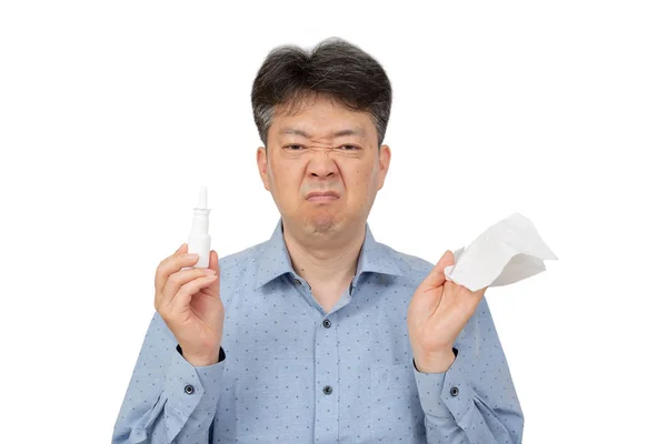 Un hombre sosteniendo un aerosol nasal en su mano sobre fondo blanco . — Foto de Stock