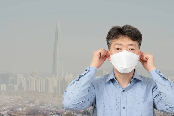 Mężczyzna w średnim wieku ubrany w maskę w tle miasta pełnego drobnego pyłu. — Zdjęcie stockowe