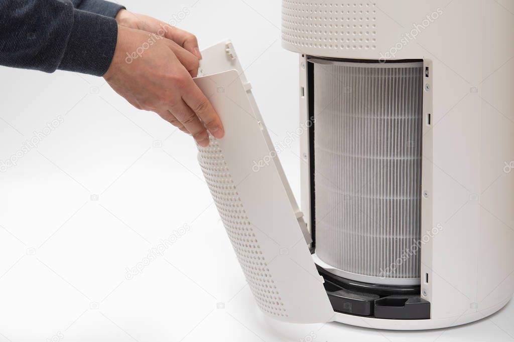 A mans hand turning an air purifiers filter into a new one.