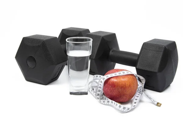 Hitam dumbbells, cup, tape measure dan apple pada latar belakang putih . — Stok Foto