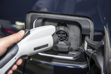 Güç kablosu kaynağı takılı şarj istasyonunda elektrikli araba. Çevre dostu alternatif enerji konsepti