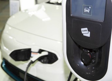 Güç kablosu kaynağı takılı şarj istasyonunda elektrikli araba. Çevre dostu alternatif enerji konsepti