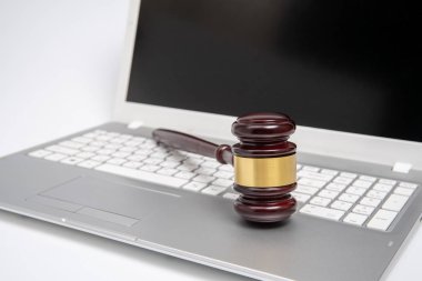 Gümüş bir dizüstü bilgisayar, siber hukuk veya online açık artırma kavramı ahşap yargıç tokmak.