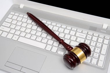 Gümüş bir dizüstü bilgisayar, siber hukuk veya online açık artırma kavramı ahşap yargıç tokmak.