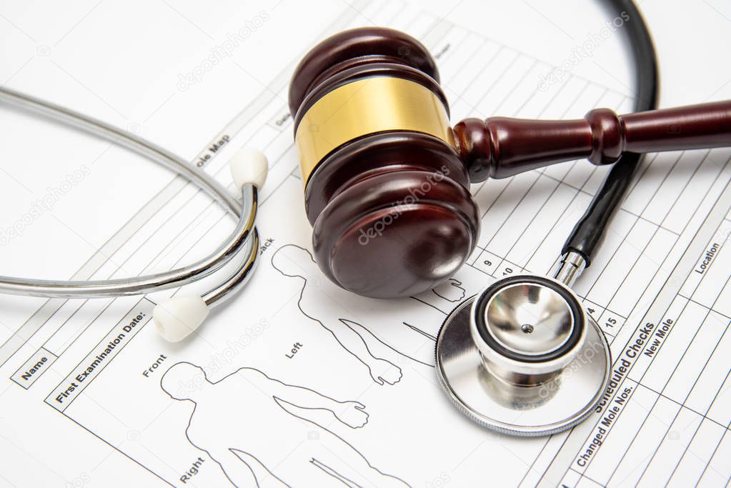 A wooden judge gavel and stethoscope on a medical chart. Medical dispute concept.