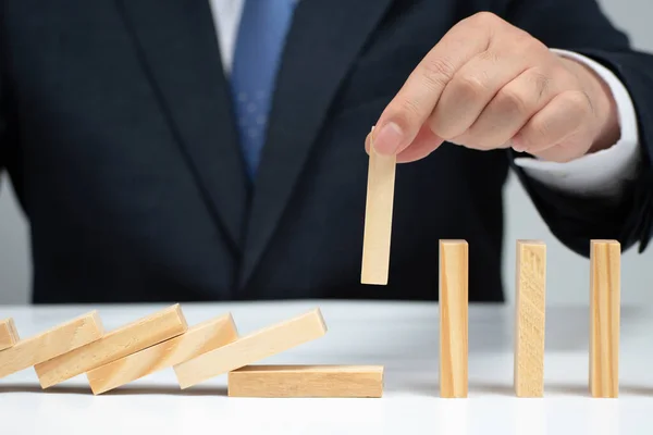 Mannelijke hand die het domino-effect stopt. Risicobeheersingsconcept. — Stockfoto