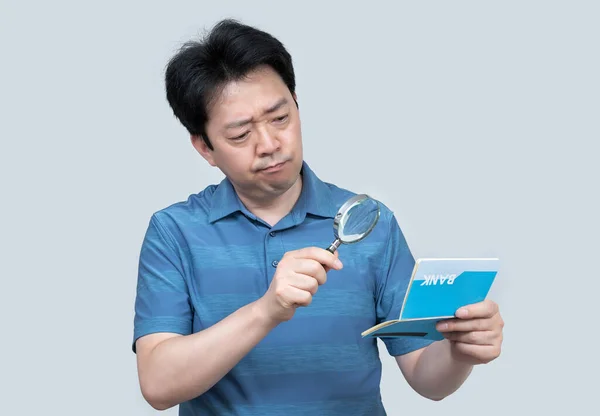 灰色の背景に彼の手に銀行券を保持している中年のアジア人男性 — ストック写真
