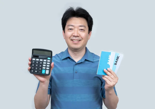 灰色の背景に彼の手に銀行券と計算機を保持している中年のアジア人男性 — ストック写真