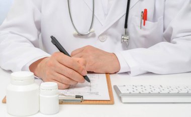 Tıbbi çizelge yazan bir erkek doktorun elleri..