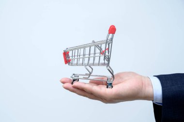 Takım elbiseli adam elinde küçük bir alışveriş arabası tutuyor. Kapatın. İş, ticaret ve alışveriş kavramı.