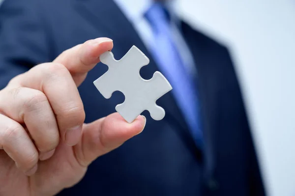 Businessman showing a jigsaw puzzle piece. Business and teamwork concept.