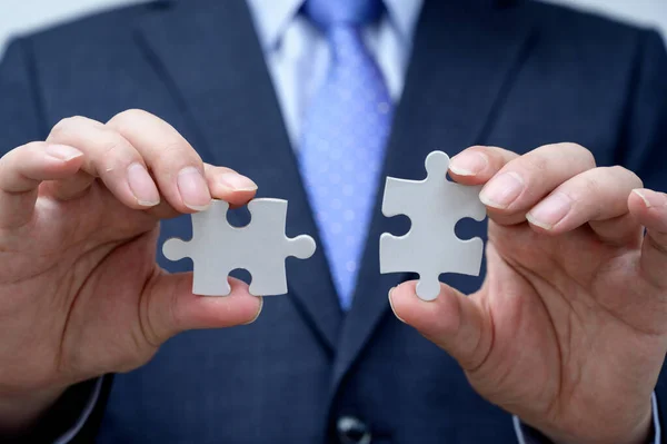 İş adamı yapboz parçası gösteriyor. İş ve takım çalışması kavramı.
