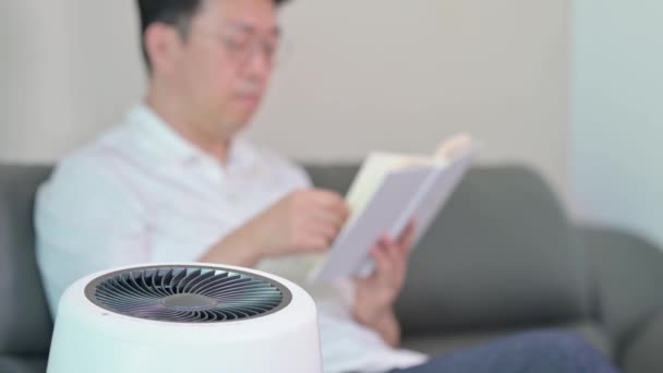 Asian Middle Aged Man Reading Living Room Air Purifier Blur — Stock Video