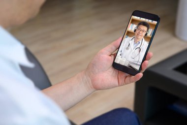 Hastanın birine uzaktan danışmanlık yapan Asyalı bir doktor. TeleHealth konsepti.