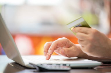 E-ticaret konsepti. Mans elinde bir kredi kartı tutuyor ve bir dizüstü bilgisayardan veri girişi yapıyor