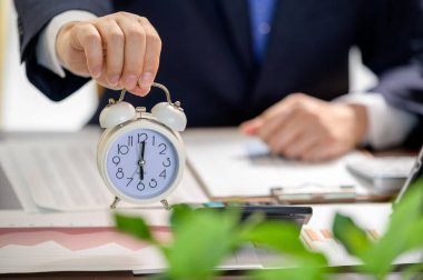 Beyaz alarmlı bir saat tutan bir iş adamı. Çalışma Zamanı kavramı.