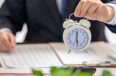 Beyaz alarmlı bir saat tutan bir iş adamı. Çalışma Zamanı kavramı.
