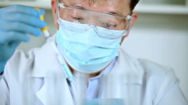 Laboratuvarda çalışan Asyalı erkek bilim adamı. Aşı geliştirme kavramı.