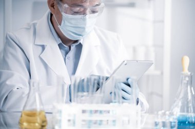 Laboratuvarda çalışan Asyalı erkek bilim adamı. Aşı geliştirme kavramı.