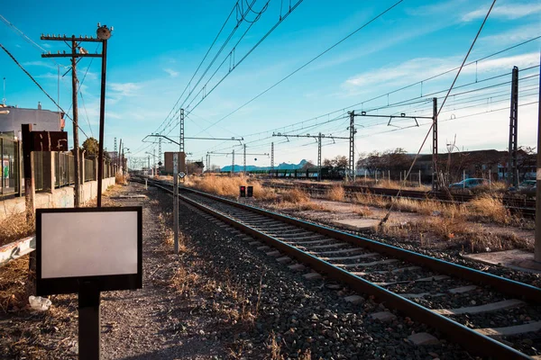 In the image can see a train tracks and there are rain changes as well.