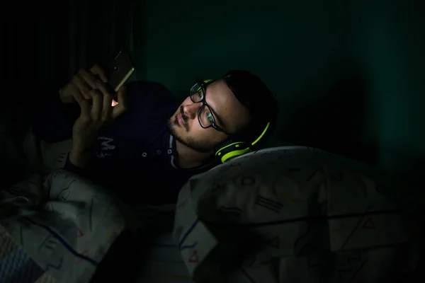 Man looking his mobile phone in the bed at night