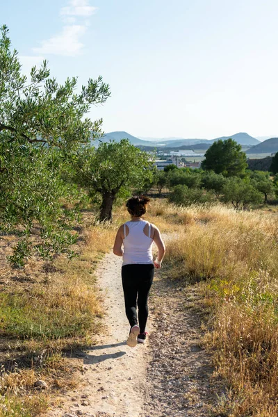 Fit middle-aged woman running through a rural field