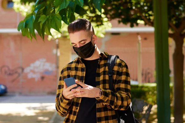 Guy with a mask writes a massage with his smartphone. Lifestyle, coronavirus