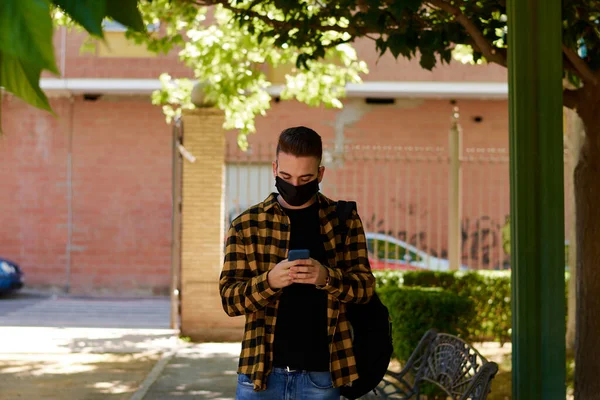 Guy with a mask writes a massage with his smartphone. Lifestyle, coronavirus