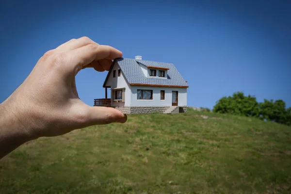 Dream to have a house. Hand holding a model house in green field
