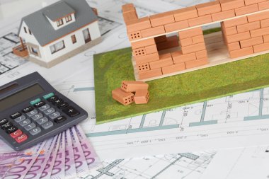 Model house construction with brick on blueprint and five hundred euro banknote clipart