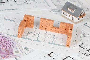 Model house construction with brick on blueprint and five hundred euro banknote clipart