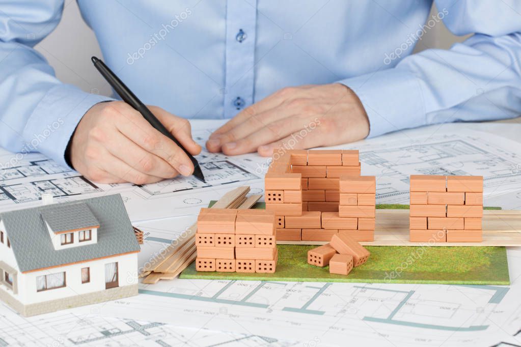 Model house construction with brick. Architect working on blueprint