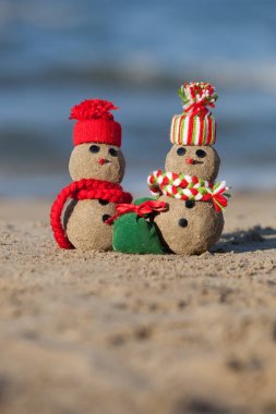 Tropik plajda iki küçük kumlu kardan adam. 