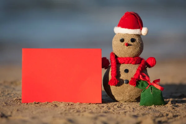 Homem de neve arenoso com cartão em branco na praia tropical . — Fotografia de Stock